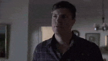 a man is standing in a dark room with his eyes closed .