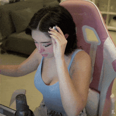 a woman in a blue tank top sits in a pink and white chair