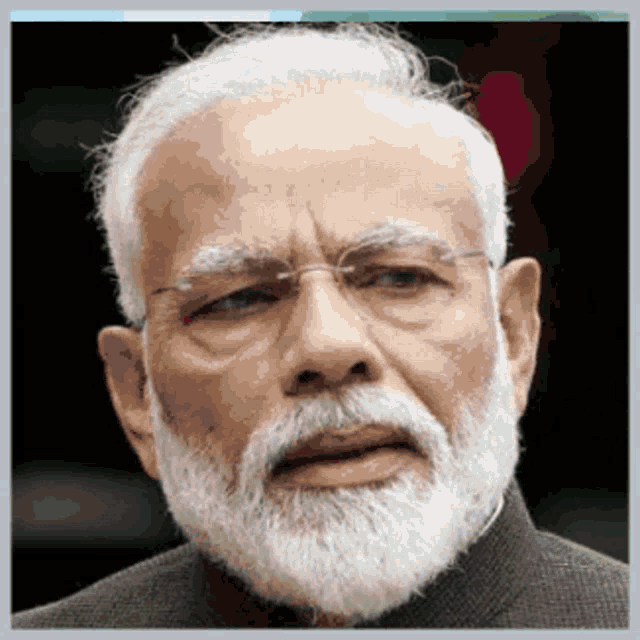 a man with glasses and a white beard looks at the camera