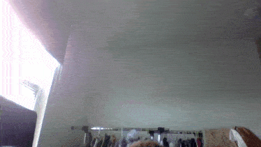 a closet with clothes hanging on a rack and a window in the background