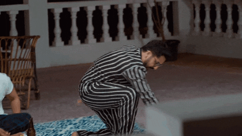 a man in striped pants is squatting down