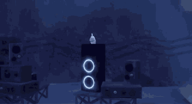 a cartoon character is standing on top of a speaker in a dark room surrounded by other speakers .