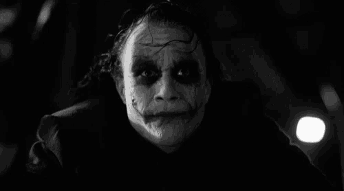 a black and white photo of the joker from the movie the dark knight rises making a funny face .