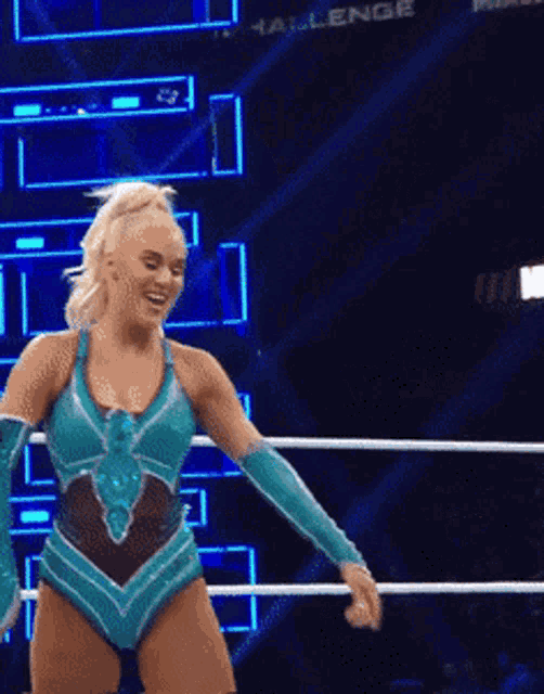 a woman in a blue leotard is standing in a ring .