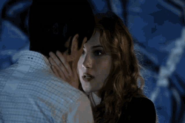 a man and woman are kissing in front of a blue wall
