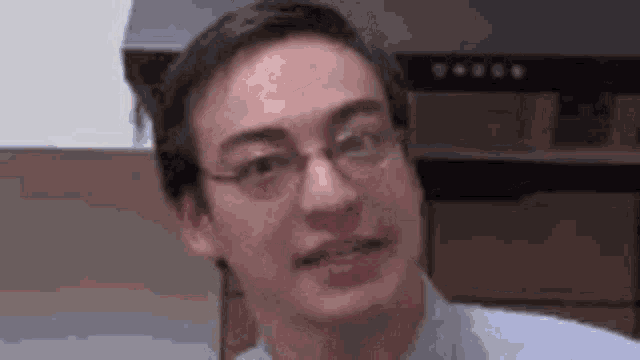 a man wearing glasses and a blue shirt is making a funny face in a kitchen .