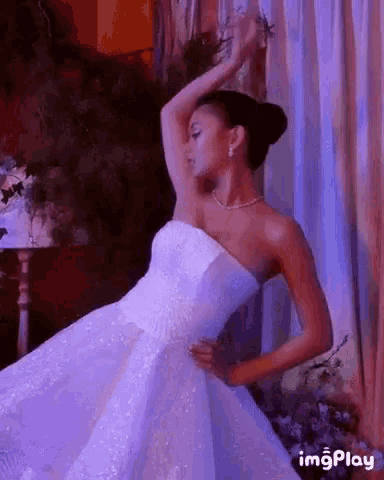 a woman in a wedding dress is dancing in a room with purple curtains .