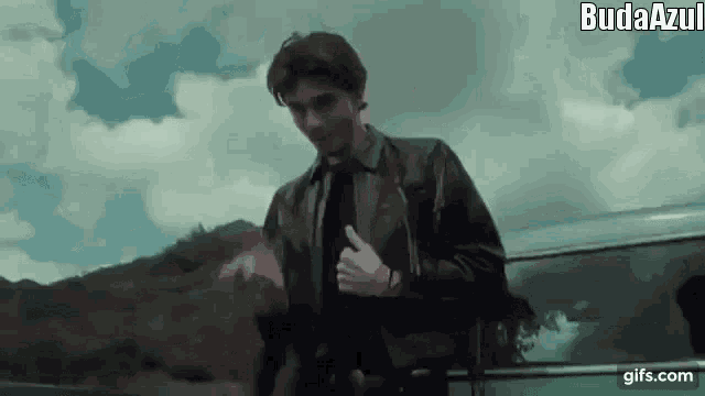 a man in a suit and tie is giving a thumbs up while standing in front of a car .