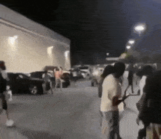 a group of people are standing in a parking lot .