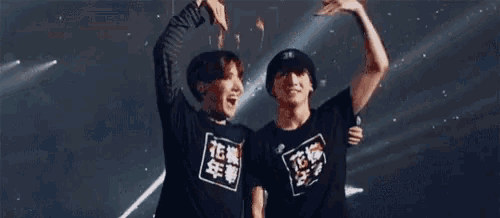 two young men are making a heart shape with their hands while standing next to each other on a stage .