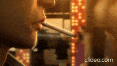 a close up of a person smoking a cigarette with the website clideo.com in the corner .