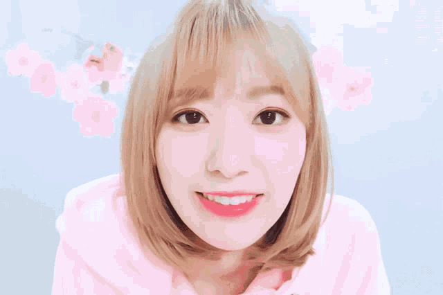 a close up of a girl with blonde hair wearing a pink hoodie