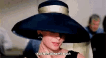 a woman wearing a black hat and a black dress is making a funny face .