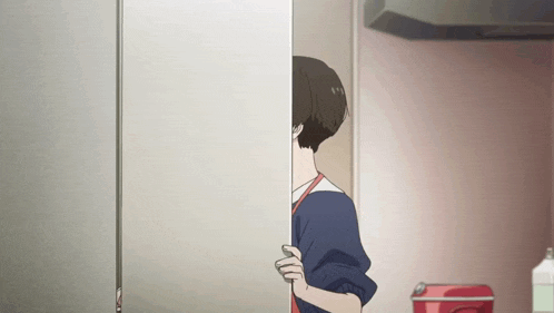 a woman is peeking out from behind a wall in a kitchen