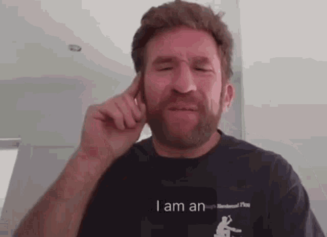 a man with a beard wearing a black shirt that says i am an