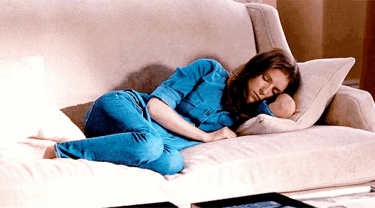a woman is laying on a couch with her head on a pillow