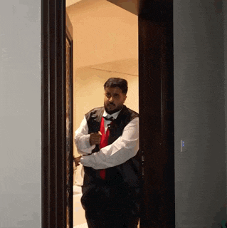a man wearing a vest and tie is standing in a doorway
