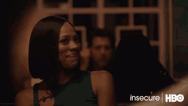 a woman is smiling in a dark room with the words insecure hbo behind her