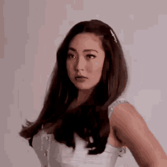 a woman in a white dress is standing in front of a white background .