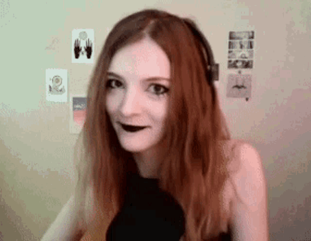a woman with long red hair wearing headphones and black lipstick