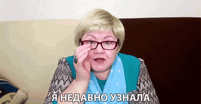 a woman wearing glasses and a blue scarf is talking in a foreign language