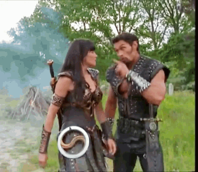 a man and a woman are standing next to each other in a field with trees in the background .