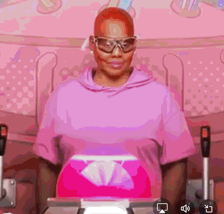 a woman in a pink hoodie is sitting in a chair with a box of tissues in front of her .