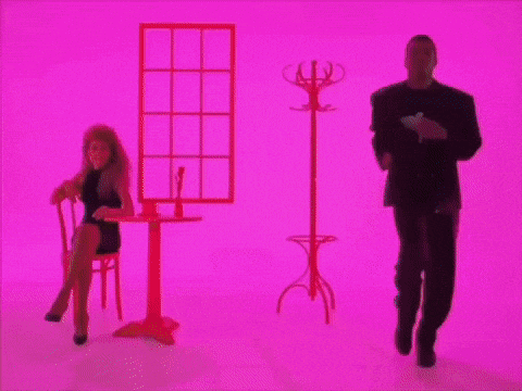 a man in a suit is dancing next to a woman in a chair