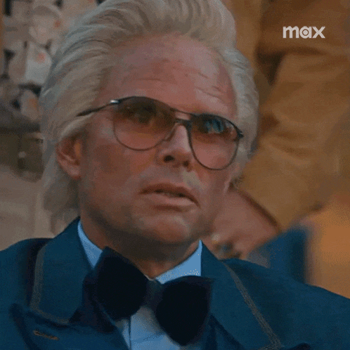a close up of a man wearing glasses and a bow tie with the word max in the corner