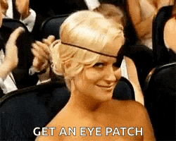 a woman wearing a eye patch is sitting in a crowd of people .