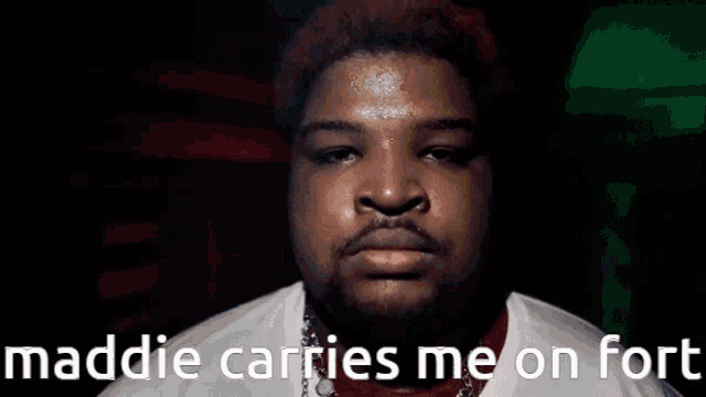 a man with red hair is looking at the camera with the words maddie carries me on fort above him .