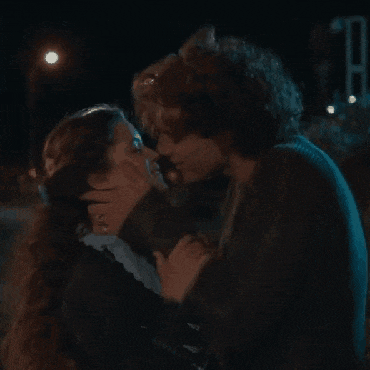 a man and woman are kissing in a dark room .