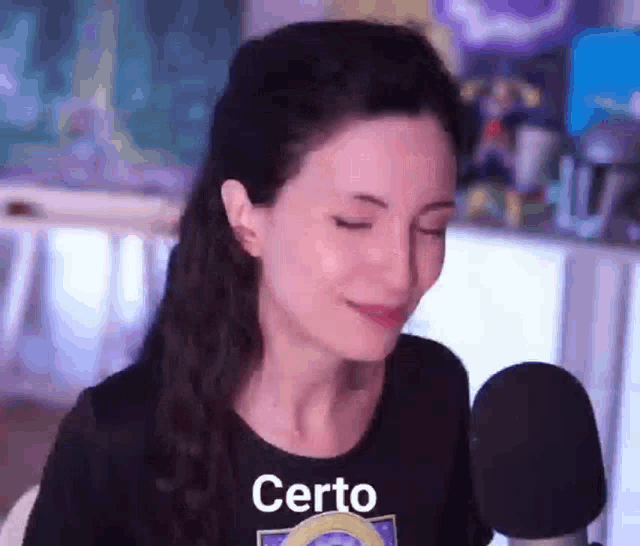 a woman is sitting in front of a microphone with her eyes closed and wearing a black shirt that says certo .
