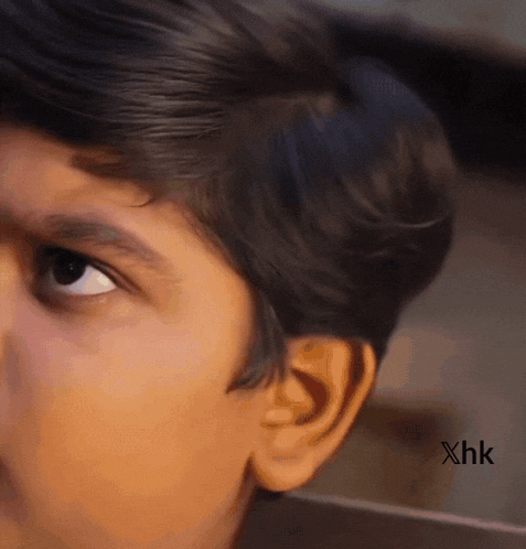 a close up of a young boy 's face with xhk written on the bottom
