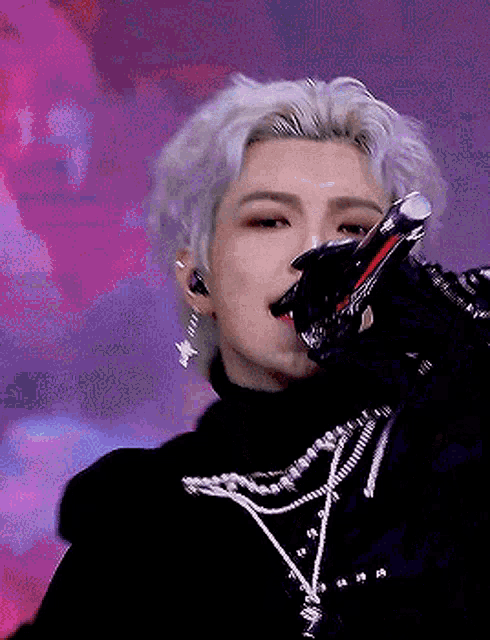 a man is singing into a microphone while wearing a black turtleneck .