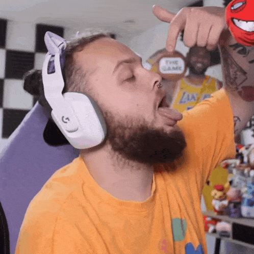 a man wearing headphones is sticking his tongue out in front of a man in a lakers jersey
