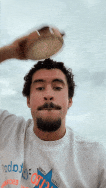 a man with a beard is wearing a white shirt that says ' todo ' on it