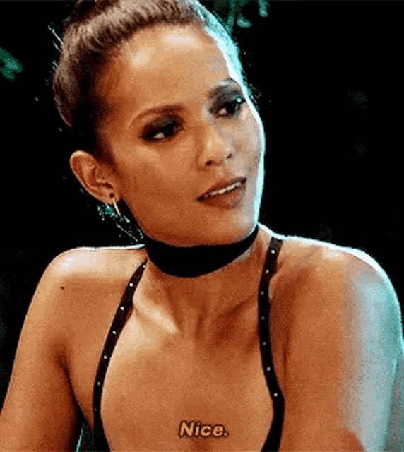 a woman wearing a choker and a black bra is talking .