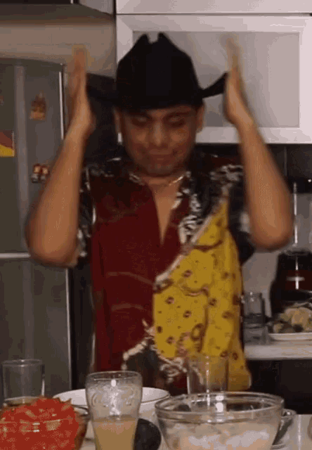 a man wearing a cowboy hat is standing in front of a bowl of guacamole