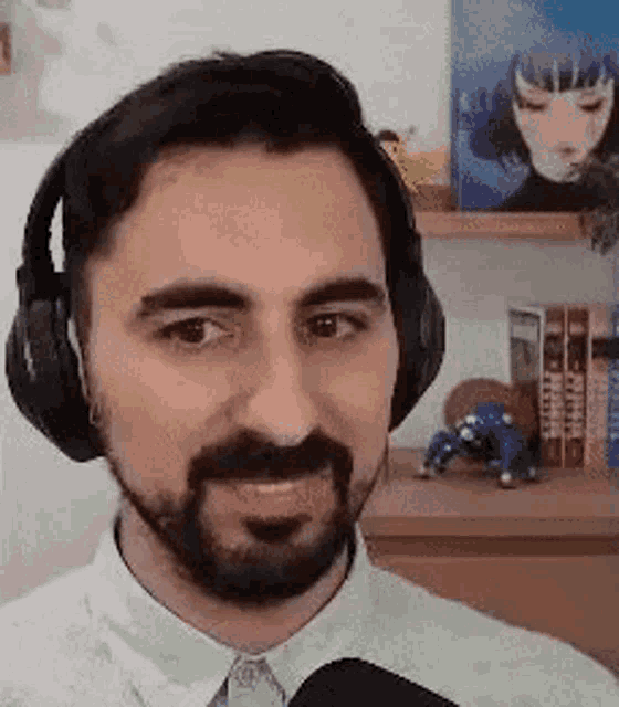a man with a beard wearing headphones and a microphone is smiling .