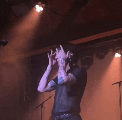 a man with tattoos on his arms is dancing on a stage in front of a microphone