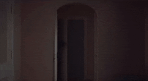 a woman is screaming while sitting on a bed in a dark bedroom .