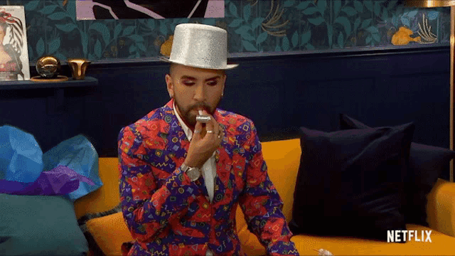 a man in a colorful suit is sitting on a couch with a netflix logo on the bottom