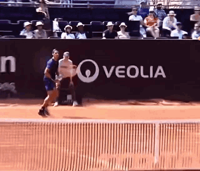 a tennis player is playing in front of a veolia sign
