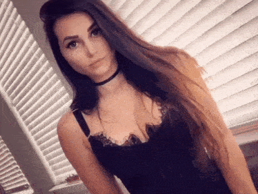 a woman with long hair is wearing a black top and a choker .