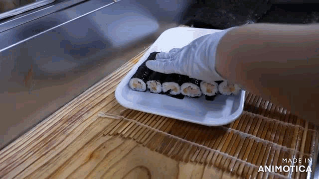 a person is putting sushi on a white plate that is made in animatica