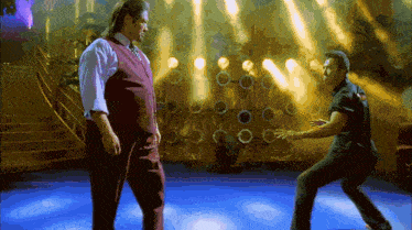 two men are dancing on a stage in front of a wall with circles on it