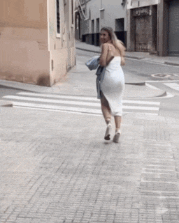 a woman in a white dress walking down a street