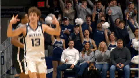 a basketball player wearing a jersey with the number 13 on it is giving a peace sign in front of a crowd .
