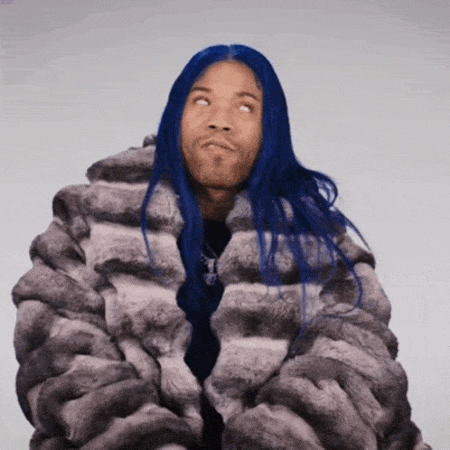 a man with blue hair and a fur coat looks up